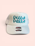White OTTO foam‑front trucker hat with teal embroidered “Dilly Dally” text and a small pink heart on the front panel.