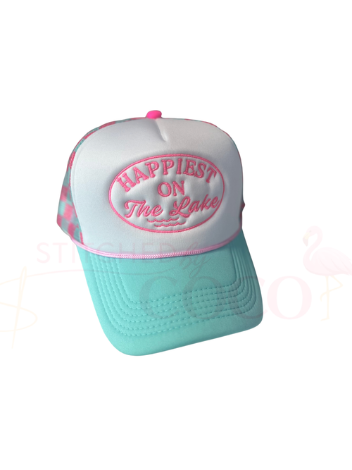 Women’s pink and teal checkered trucker hat with turquoise brim and white front panel embroidered with ‘Happiest on the Lake’ in a pink oval design