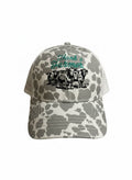 Gray and white cow‑print baseball hat with green embroidered ‘Thank a Farmer’ lettering and detailed black stitched cows on the front panel.